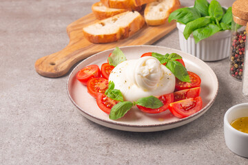 Delicious Italian caprese salad with sliced mozzarella, tomatoes, basil, and bread on background. 