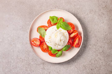 Delicious Italian caprese salad with sliced mozzarella, tomatoes, basil, and bread on background. 