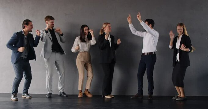 Group of young excited business people men and women having fun in office happy to make a good deal. Company employees celebrating success dancing indoors. Success and teamwork concept. 4k video.