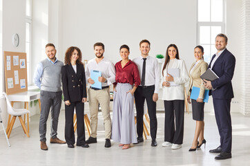 Group of business people men and women looking cheerful at camera and smiling indoors. Company...