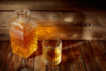 Elegant whiskey glass and decanter on a old wooden table.