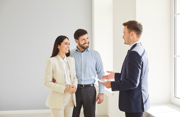 Family couple and male realtor showing new room, making real estate offer presenting purchase...