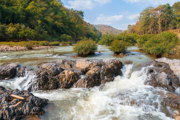 The landscape features a forest with rock formations and a stream flowing through the middle.