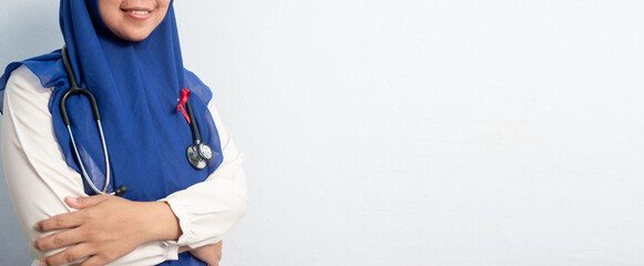 Close up Muslim Female Asian doctor or nurse wearing Red ribbons on cloth, HIV awareness concept, world AIDS day, world cancer day. Isolated white background.