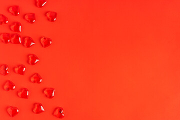 Top view of bright red background with copy space with festive transparent glass heart shaped decoration used for celebration of valentines day holiday or greeting card for romantic dinner party