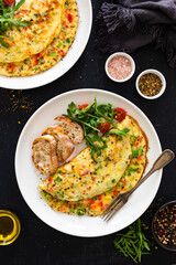 Omelette - scrambled eggs with red and green bell pepper on black table	