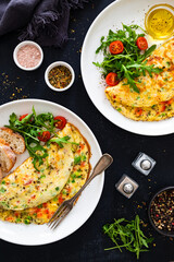 Omelette - scrambled eggs with red and green bell pepper on black table	