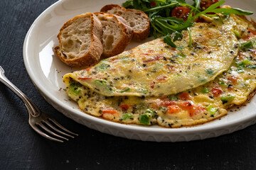 Omelette - scrambled eggs with red and green bell pepper on black table	