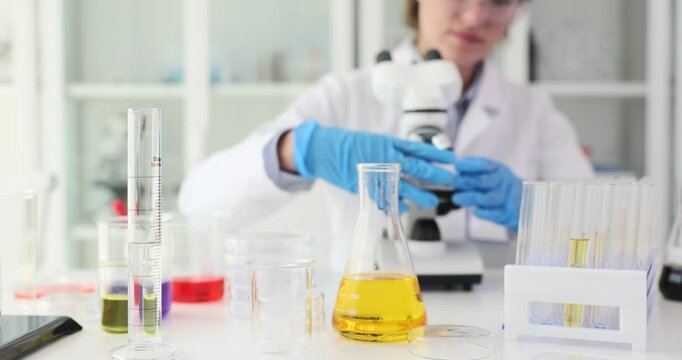Scientist places glass slide with sample under microscope. Laboratory assistant observes microscopic structures of specimen. Slow motion - Powered by Adobe