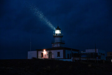 Faro de noche iluminando mientras llueve
