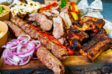 Grilled meats showcase on a wooden platter with sides and garnishes