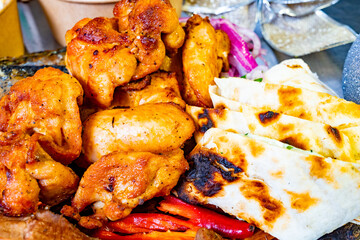 Grilled chicken and flatbreads served with fresh vegetables at outdoor gathering