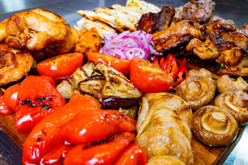 Grilled meat and vegetables served on a wooden platter at a summer gathering