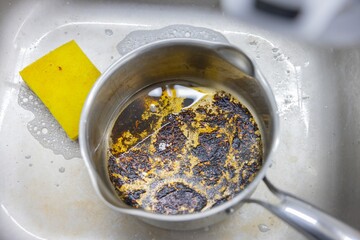 Burned pot in the sink with black char