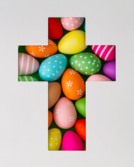 Spring composition with colored Easter eggs visible through a cross shaped gap on white background. Minimal Easter concept. Creative festive holiday layout. Easter aesthetic. Flat lay, top of view.
