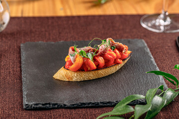 Portion of gourmet bruschetta with baked peppers and anchovies