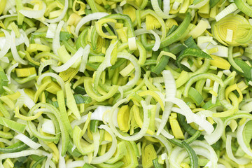 Chopped leek for salad. Vegetable cut in pieces. Fresh vegetables preparation. Green health background. Shredded leek for side dish. Closeup food texture.