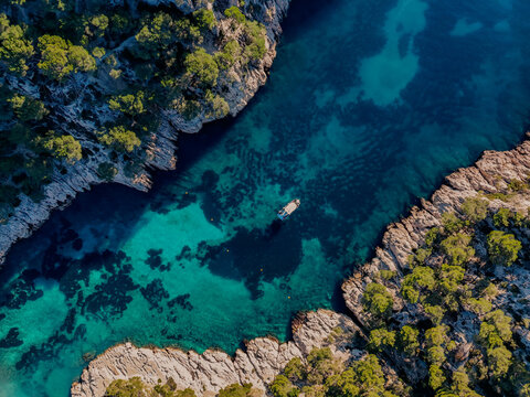 Aerial view of Calanque de Port Pin Beach with boat, rocks and trees in Marseille, France
