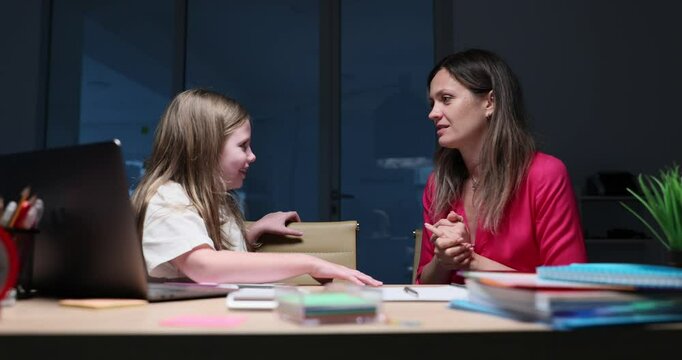 Stressed mother criticizes daughter academic performance leaning over desk with laptop and books. Intense family communication challenge slow motion