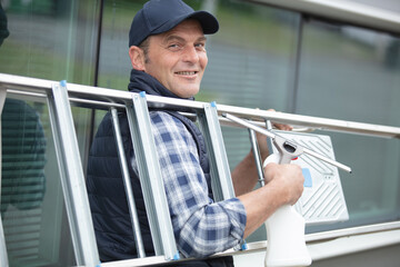 maintenance worker man carrying aluminium step ladder at construction site © auremar