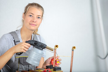 female plumber using blowtorch on copper pipes