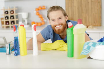 portrait of a male cleaner man with detergent bottles