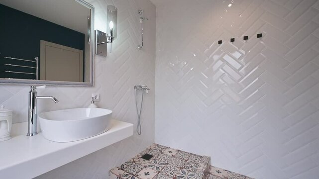 modern bathroom with white herringbone tiles, a white countertop with a round sink, a mirror, and a chrome faucet