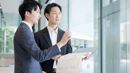 図面を持ち打ち合わせをするビジネスマン