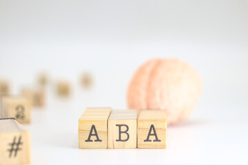 Applied behavior analysis acronym. ABA written on wooden cubes isolated with a figure of a brain on white background with space for text.