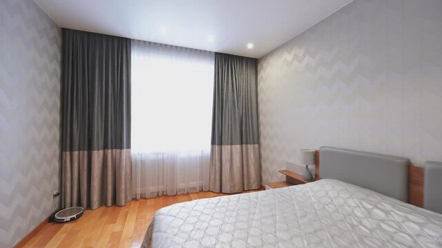 A modern bedroom with a bed, curtains, wooden floors, bedside tables, and a dresser. Neutral color palette creates a calm and inviting atmosphere.
