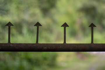 Close-up shot of a metallic fence with four spikes. Beautiful green background. Tierradentro, Cauca, Colombia.