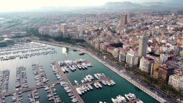 Drone circling above the city center and marina of Alicante. Famous travel destination in Spain. Sunset point with orange and pink reflections. Panoramic view of all region. Summer destination.