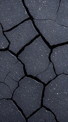 Obraz premium Close-up of cracked black asphalt pavement showing deterioration and wear over time