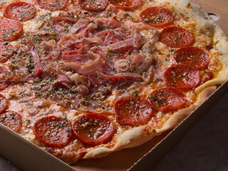 Pizza na caixa de papelão com queijo mozarela e vários sabores e condimentos, feita de massa fina, farinha