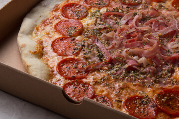 Pizza na caixa de papel&atilde;o com queijo mozarela e v&aacute;rios sabores e condimentos, feita de massa fina, farinha