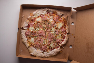 Pizza na caixa de papel&atilde;o com queijo mozarela e v&aacute;rios sabores e condimentos, feita de massa fina, farinha