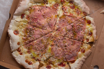 Pizza na caixa de papel&atilde;o com queijo mozarela e v&aacute;rios sabores e condimentos, feita de massa fina, farinha