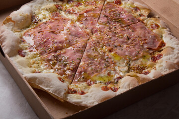 Pizza na caixa de papel&atilde;o com queijo mozarela e v&aacute;rios sabores e condimentos, feita de massa fina, farinha