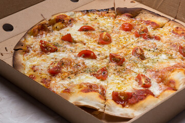 Pizza na caixa de papelão com queijo mozarela e vários sabores e condimentos, feita de massa fina, farinha