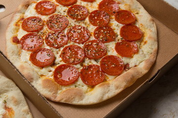 Pizza na caixa de papel&atilde;o com queijo mozarela e v&aacute;rios sabores e condimentos, feita de massa fina, farinha