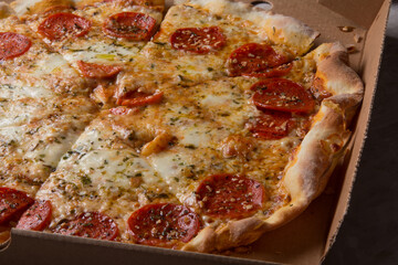 Pizza na caixa de papel&atilde;o com queijo mozarela e v&aacute;rios sabores e condimentos, feita de massa fina, farinha