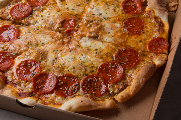 Pizza na caixa de papelão com queijo mozarela e vários sabores e condimentos, feita de massa fina, farinha