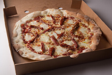 Pizza na caixa de papel&atilde;o com queijo mozarela e v&aacute;rios sabores e condimentos, feita de massa fina, farinha