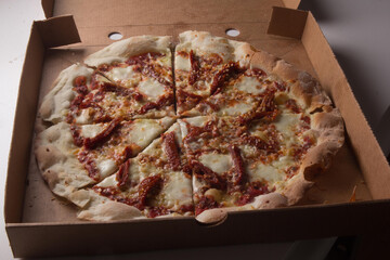 Pizza na caixa de papel&atilde;o com queijo mozarela e v&aacute;rios sabores e condimentos, feita de massa fina, farinha