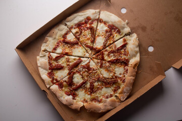 Pizza na caixa de papel&atilde;o com queijo mozarela e v&aacute;rios sabores e condimentos, feita de massa fina, farinha