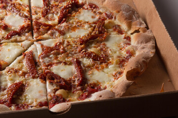 Pizza na caixa de papel&atilde;o com queijo mozarela e v&aacute;rios sabores e condimentos, feita de massa fina, farinha