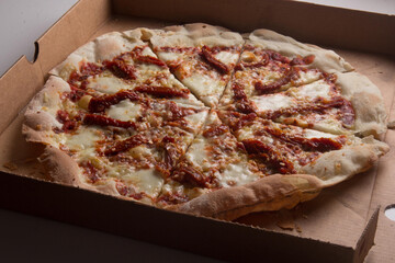 Pizza na caixa de papel&atilde;o com queijo mozarela e v&aacute;rios sabores e condimentos, feita de massa fina, farinha