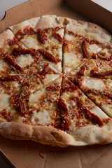 Pizza na caixa de papel&atilde;o com queijo mozarela e v&aacute;rios sabores e condimentos, feita de massa fina, farinha