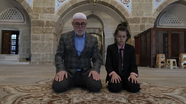 Grandfather and grandson perform salaat 
