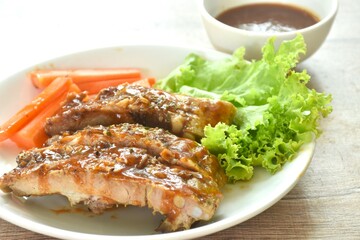 grilled pork rib with carrot and lettuce on plate dipping barbecue sauce cup